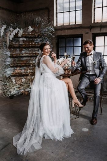 Industrial Wedding Sektempfang mit Sektglaswand und Brautpaar