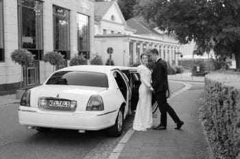 Brautpaar neben Limousine