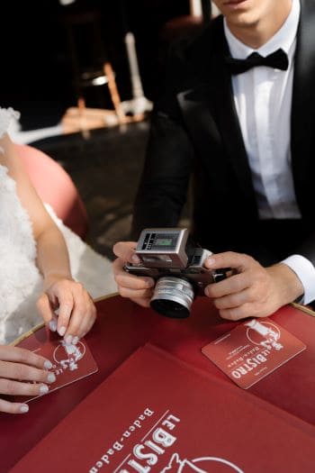 Brautpaar am Bistrotisch mit alter Kamera in der Hand